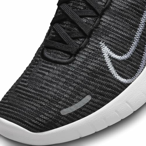 Closeup of a black knitted sneaker with a white sole.