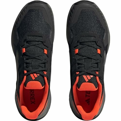 Top view of black sport shoes with orange accents.